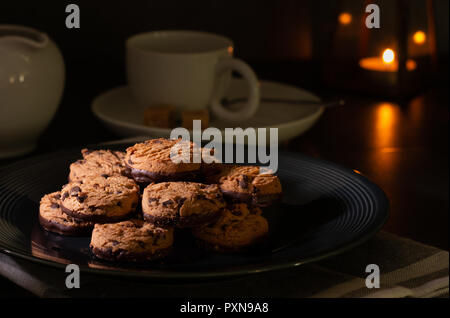 Homemade chocolate chip cookies on a kitchen table with milk, dark chocolate and a cup of coffee. Stock Photo