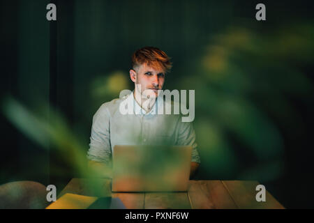 Man sitting in office, working late in his start-up company Stock Photo