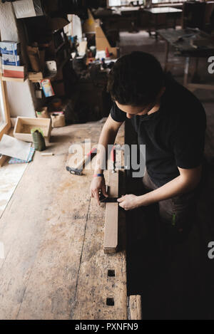 Carpenter measuring piece of wood in workshop Stock Photo