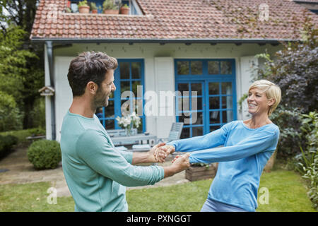 Happy couple dancing in front of their home Stock Photo