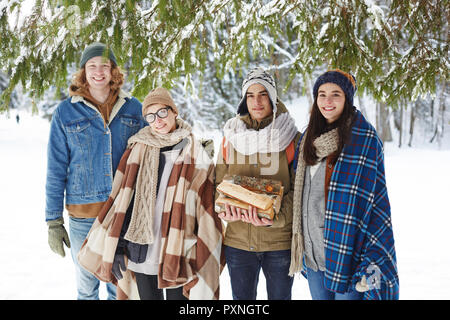Portrait of two beautiful young couples posing in snowy forest enjoying winter resort and vacation Stock Photo
