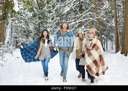 Full length portrait of modern young people walking towards camera in winter resort and laughing happily Stock Photo