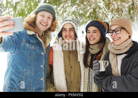 Waist up portrait of  happy young people taking selfie in beautiful snowy forest on winter resort Stock Photo