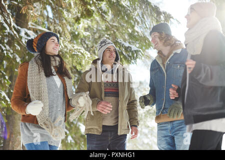 Group of happy young people chatting during walk in beautiful winter forest and enjoying vacation Stock Photo