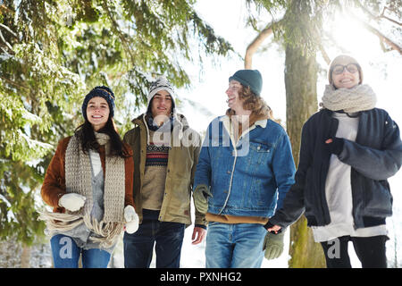 Group of happy young people enjoying walk in beautiful winter forest during vacation Stock Photo