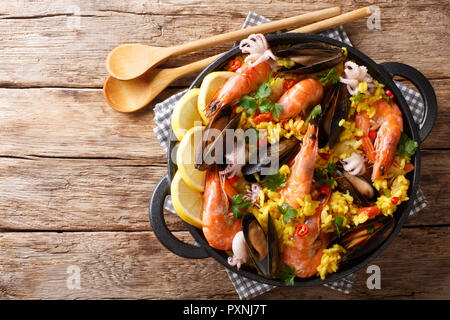 Spanish traditional cuisine: hot paella with seafood shrimps, mussels, fish, and baby octopuses close-up in a frying pan on the table. Horizontal top  Stock Photo