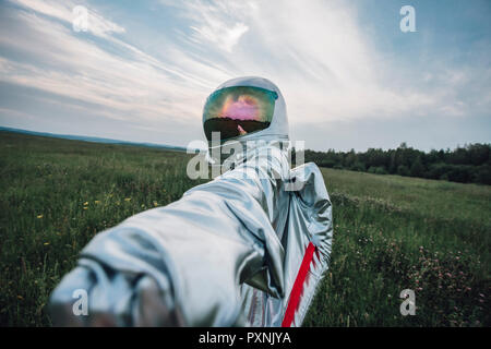 Spaceman exploring nature, reaching out hand Stock Photo