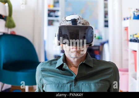Portrait of mature man at home using Virtual Reality Glasses Stock Photo
