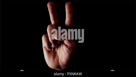 Hand making the peace sign. Emotionally and beautifully lite. On black background Stock Photo