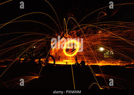 Burning steel wool spinned in the forest. Showers of glowing sparks from spinning steel wool. Stock Photo