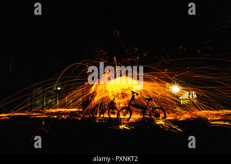 Burning steel wool spinned in the forest. Showers of glowing sparks from spinning steel wool. Stock Photo