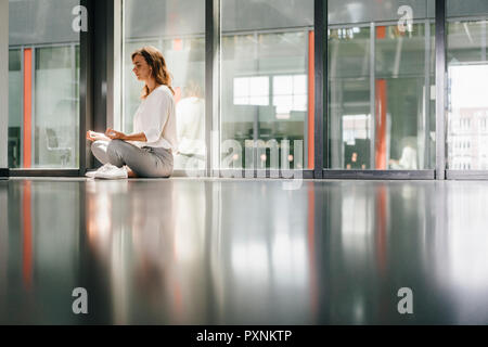 Businesswoman practicing yoga in office, meditating Stock Photo