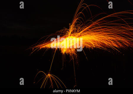 Burning steel wool spinned in the forest. Showers of glowing sparks from spinning steel wool. Stock Photo