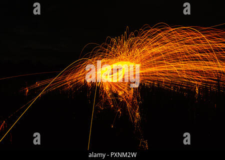 Burning steel wool spinned in the forest. Showers of glowing sparks from spinning steel wool. Stock Photo