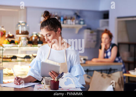 Woman working in a cafe taking notes Stock Photo