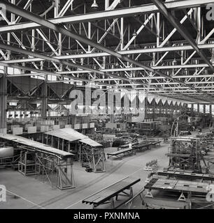 1950s, historical picture showing aircraft being built or assembled inside a large hanger or factory, England, UK. In the foreground, one can see parts of the wings being constructed. Stock Photo