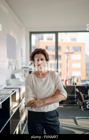 Successful businesswoman standing in her office with arms crossed Stock Photo