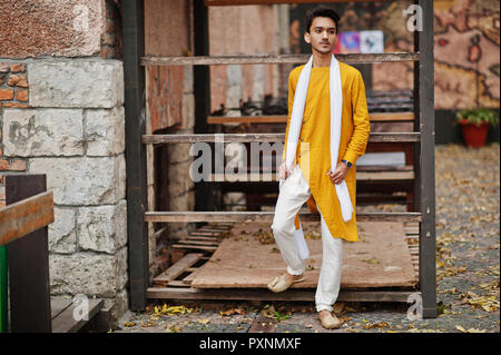 indian stylish man in yellow traditional clothes with white scarf posed outdoor
