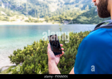 Austria, Tyrol, Hiker using compass app at Lake Seebensee Stock Photo