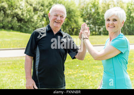 Senior couple running in park doing high five Stock Photo