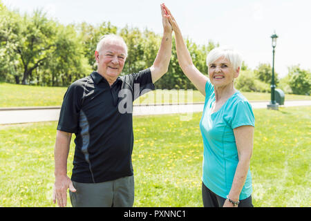 Senior couple running in park doing high five Stock Photo