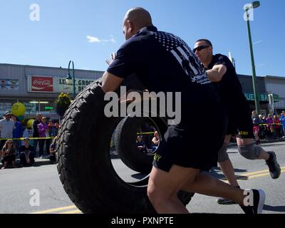 Ace Ventura (left) and Mark Nieto, members of the Alaska Army National Guard team Swole Patrol, participate in a tire-roll challenge during the 2017 Hero Games June 17, 2017, as part of Anchorage's Downtown Solstice Festival. Two members rolled the tire before the whole team was required to flip the tire back to the start line. Stock Photo