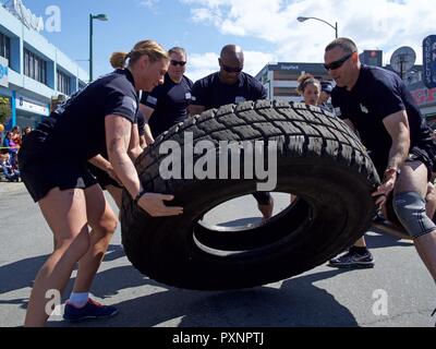 The Alaska Army National Guard team Swole Patrol participates in a tire-roll challenge during the 2017 Hero Games June 17, 2017, as part of Anchorage's Downtown Solstice Festival. Two members rolled the tire before the whole team was required to flip the tire back to the start line. Stock Photo