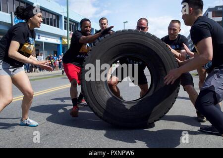 The Alaska Air National Guard team Arctic Guardians participates in a tire-roll challenge during the 2017 Hero Games June 17, 2017, as part of Anchorage's Downtown Solstice Festival. Two members rolled the tire before the whole team was required to flip the tire back to the start line. Stock Photo