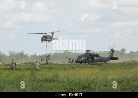 Soldiers from Alpha Battery, 1st Battalion, 118th Field Artillery, 48th Infantry Brigade Combat Team move towards Sikorsky UH-60 Blackhawk helicopters to guide 119A3 Howitzer cannons into firing positions June 18, 2017 during the eXportable Combat Training Capability exercise at Fort Stewart, Ga. This air assault gun raid tested cannon crewmembers from Alpha Battery, 1st Battalion, 118th Field Artillery, 48th Infantry Brigade Combat Team, 3rd Infantry Division in executing a fire mission. Stock Photo