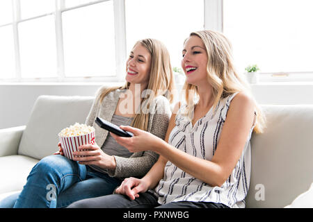 Two friends watching movie at home with popcorn Stock Photo