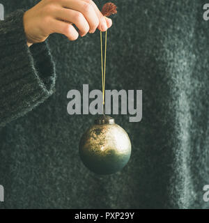 Woman in grey sweater holding decorative golden ball, square crop Stock Photo