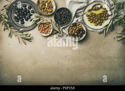 Mediterranean pickled olives and olive tree branches on grey background Stock Photo