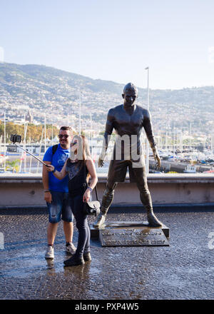 Couple taking a selfie near of the statue of the famous football (soccer) player 'Cristiano Ronaldo' in Funchal city, Madeira island, Portugal, Octobe Stock Photo