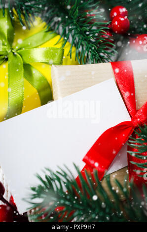 Christmas background with decorations and gift boxes on knitted board blanket. Xmas presents with blank postcard. Snow Falling Effect. Stock Photo