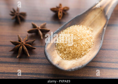 brown sugar in the spoon and anise on the table. Stock Photo