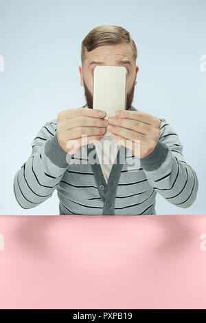 Surprised business man talking on phone sitting at the table. Concept of male emotions Stock Photo