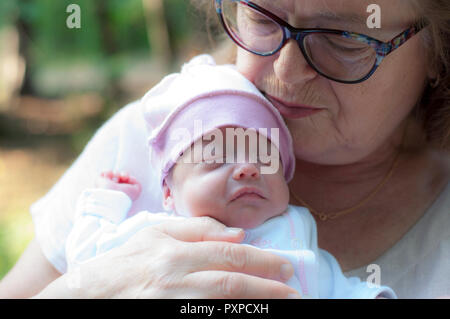 Grandmother holds a small newborn granddaughter in her arms. Stock Photo