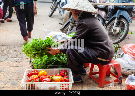 DA LAT, VIETNAM - SEPTEMBER 23: A senior woman sells greens and paprika on the street on September 23, 2018 in Da Lat, Vietnam. Stock Photo