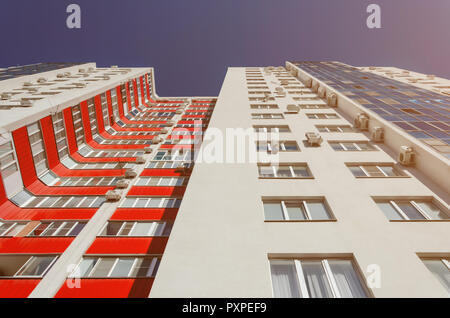 View of a residential building from the bottom up. White house with red balconies in a warm sunny day