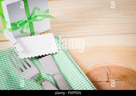 Dining Table Setting. Cutlery with Empty Tag and Present on Linen Napkin on Rustic Wooden Background. Spring Concept. Copy Space. Selective Focus. Stock Photo