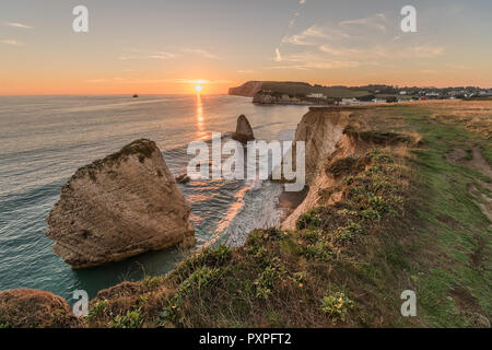Freshwater Sunset. A autumnal sunset with a sun ladder between the Stag and Mermaid Rocksat Freshwater, Isle of Wight Stock Photo