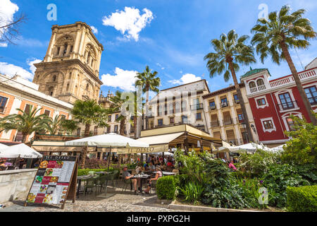 Granada, Andalucia, Spain - April 16, 2016: tourists eat at restaurant El Deseo in Plaza de las Romanillas. On background the Tower of Granada Cathedral in a sunny day. Stock Photo
