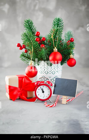 Christmas composition: xmas fir branches, alarm clock, gift box and decorations. Christmas still life, greeting postcard. Stock Photo