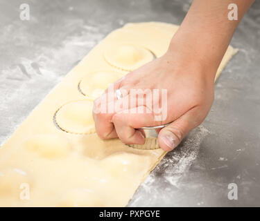 A woman's hand cutting rolled out ravioli dough into circles. Stock Photo