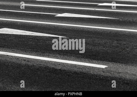 Driving directions by lanes. White arrows and lines, road marking on dark highway asphalt Stock Photo
