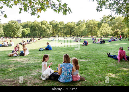 London England,UK,Green Park,Ritz Corner,Royal Parks,lawn,outdoors,green space,sitting on grass,woman female women,girl girls,kid kids child children Stock Photo
