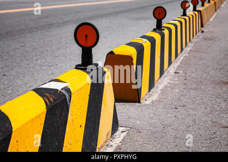 Concrete blocks with caution pattern, road fence with reflectors Stock Photo