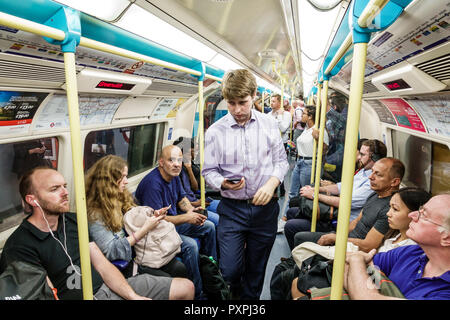 London England,UK,underground subway tube,train,carriage,inside interior,commuters,passenger passengers rider riders,man men male,woman female women,B Stock Photo