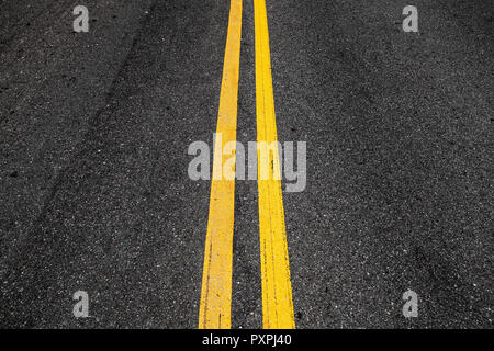 Yellow double dividing lines, highway road marking on dark asphalt Stock Photo