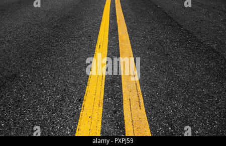 Yellow double dividing lines perspective view, highway road marking on dark asphalt Stock Photo